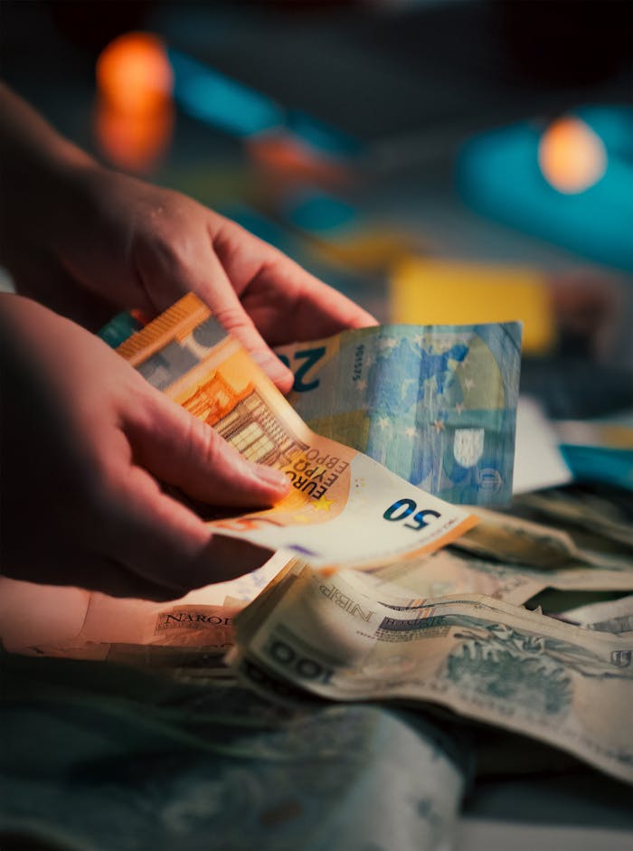 Hands counting assorted Euro banknotes, highlighting currency exchange and finance concepts.